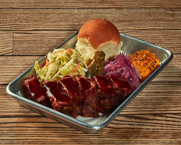 Baked pork loin with barbecue sauce and vegetable garnish on plastic tray — Stock Photo, Image