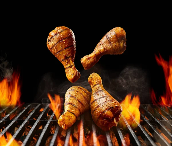 Falling down barbecue bbq grilled chicken drumsticks with golden crust and spices. Flaming fire, ember charcoal, smoke on black background. Close up — Stock Photo, Image