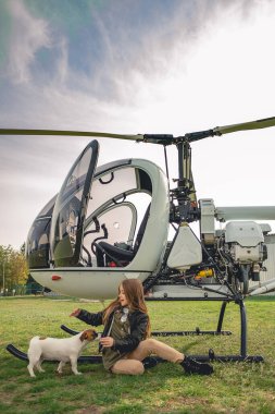 Neşeli genç kız helikopterin yanında köpek yavrusuyla oynuyor.