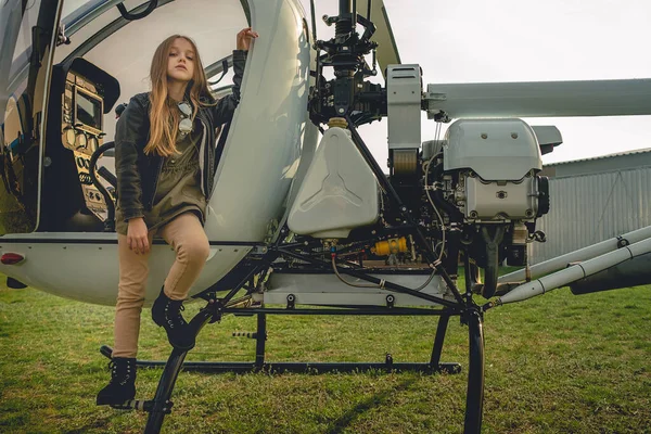 Tween lány pózol közelében nyitott pilótafülke helikopter — Stock Fotó