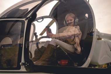 Helikopter kontrolünü taklit eden genç bir kızın kokpitinin camından bak.