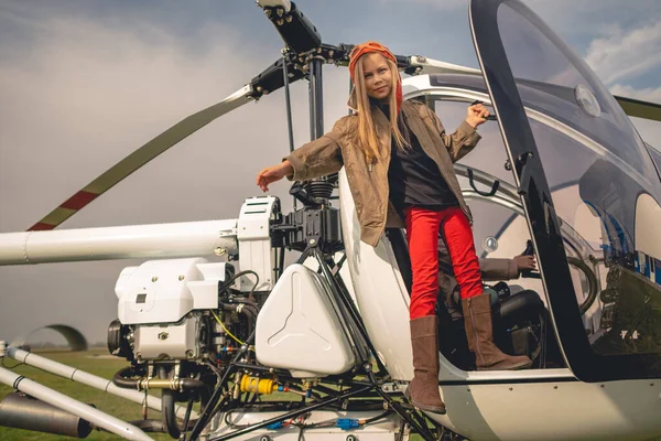 Preteen lány pilóta kalap áll a nyitott helikopter pilótafülkében — Stock Fotó