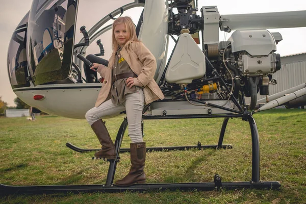 Szőke tizenéves lány pózol közelében nyitott helikopter a reptéren — Stock Fotó