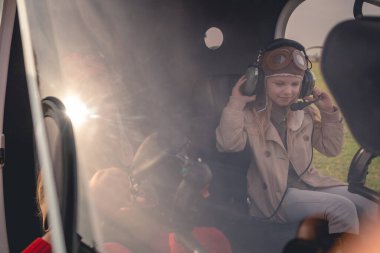 Tween girl putting on headset on pilot seat in helicopter clipart