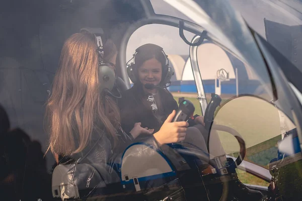 Vidám tizenéves lányok fülhallgatóban, akik helikopterpilótafülkében beszélgetnek. — Stock Fotó