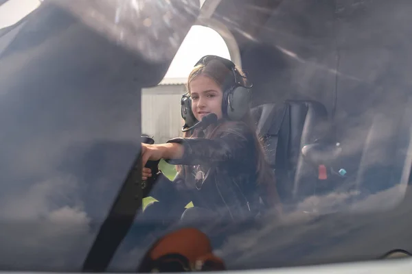 Vista a través de cristal de la muchacha de Tween en la cabina del helicóptero que alcanza hacia fuera al tablero de instrumentos — Foto de Stock