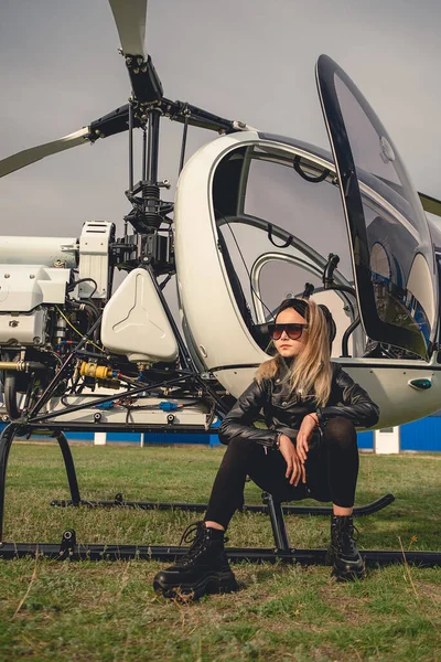 Selbstbewusstes blondes Zwillingsmädchen sitzt auf Landebahn von Hubschrauber — Stockfoto