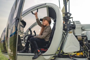 Modern helikopter kokpitinde pilot koltuğunda oturan genç kız.