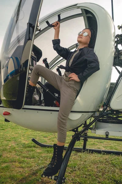 Hübsches Mädchen mit verspiegelter Sonnenbrille blickt von Hubschrauberschritten in den Himmel — Stockfoto