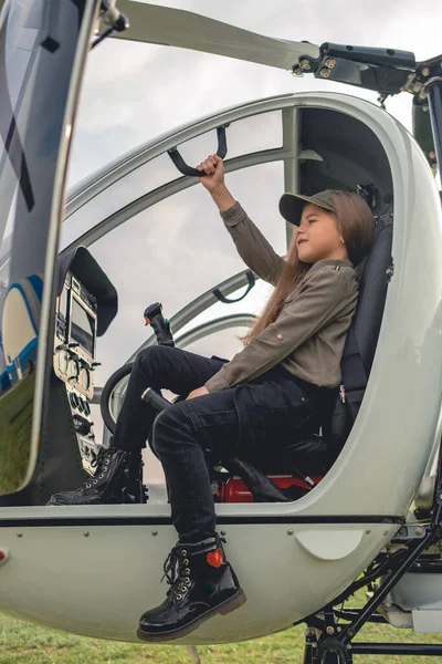 Mosolygó tizenéves lány ül pilótafülkében nyitott helikopter pilótafülkében — Stock Fotó
