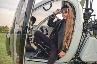 Helikopterin açık kokpitinde oturan kendinden emin genç kız.