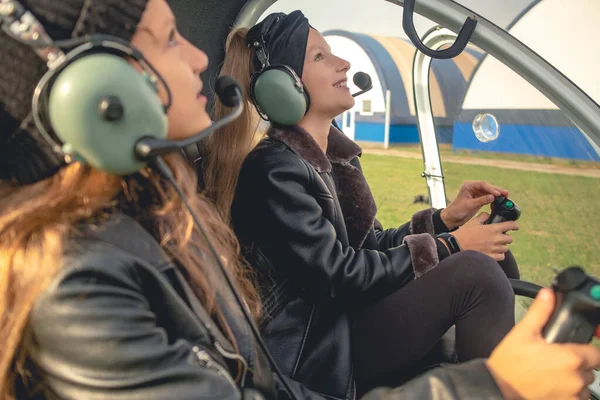 Mosolygó tizenéves lányok fülhallgatóban, akik felnéznek az égre a helikopterpilótafülkében. — Stock Fotó