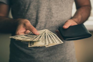 Bir adamın elinde dolar ve siyah cüzdan var.