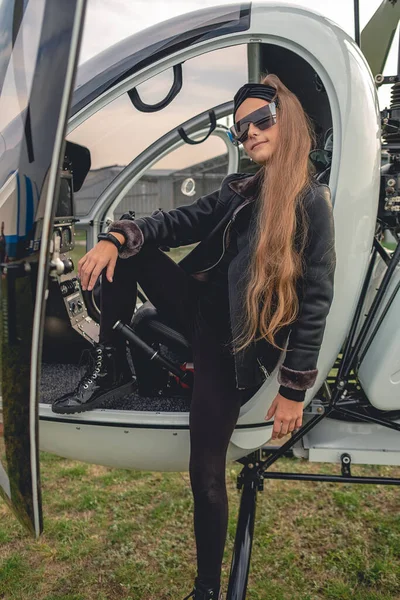 Stílusos tizenéves lány áll a fedélzeten a helikopter — Stock Fotó