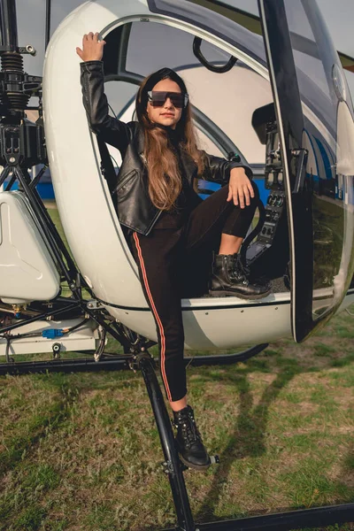 Девочка-подросток в солнечных очках стоит на подножии вертолета — стоковое фото