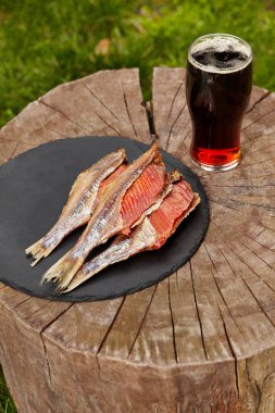 Güneşte kurutulmuş hamamböceği ve tahta kütüğün üzerinde bir bardak koyu bira.