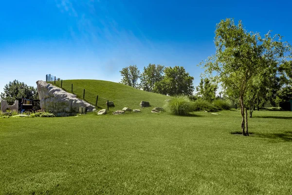 Park alanı, kayaların yamacında çimen ve çocuk parkı. — Stok fotoğraf