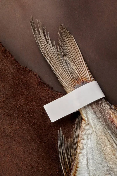 Соленый хвост таракана с бумажной этикеткой на коричневом кожаном фоне — стоковое фото