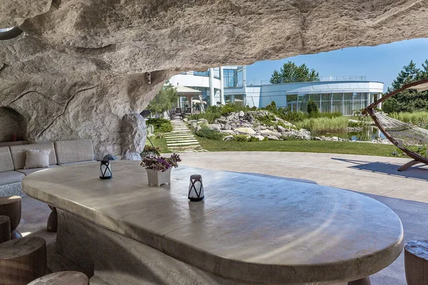Μαρμάρινο τραπέζι σε βραχώδη σπηλιά που έχει συσταθεί κάτω από το αίθριο στο κτήμα χώρα με διαμορφωμένο κήπο — Φωτογραφία Αρχείου