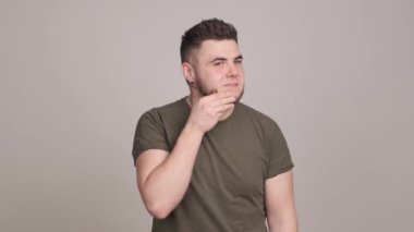 Endişeli genç sakallı adam cildini inceliyor.