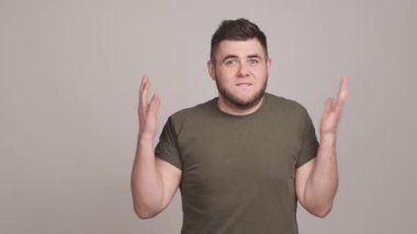 Elleriyle küfreden ve el kol hareketi yapan sinirli ve şok olmuş genç bir adam.