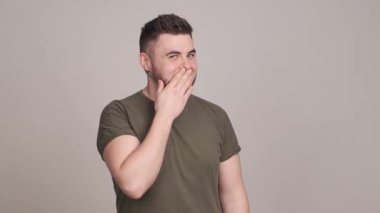 Gülümseyen adam utangaç bir şekilde elleri ve ağzı örtüyor.