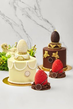 Çikolatalı yumurta ve altın detaylarla süslenmiş lezzetli paskalya pastaları bayram kutlaması için bir şenlik merkezi oluşturuyor.