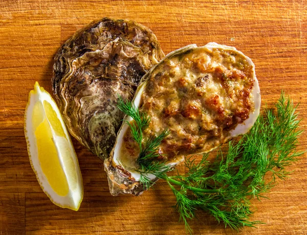 Baked oyster shell with cheese, served greens and lemon — Stock Photo, Image