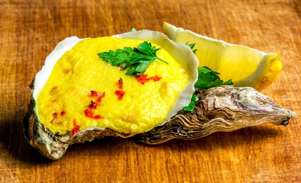 Baked oyster shell with cheese, served greens and lemon — Stock Photo, Image