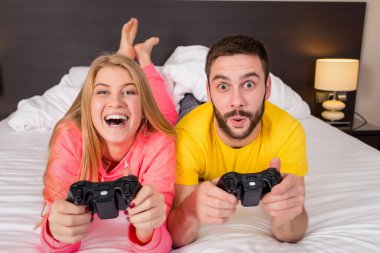 Eğleniyor mutlu genç çift yatakta video oyunları oynarken