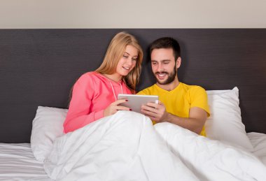 Young Sweet Couple at Bed Watching Something on Tablet Gadget