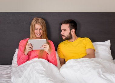 Young Sweet Couple at Bed Watching Something on Tablet Gadget