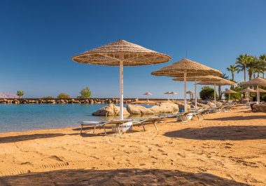 Hasır şemsiyeler ve harika tropik sahilde şezlong.