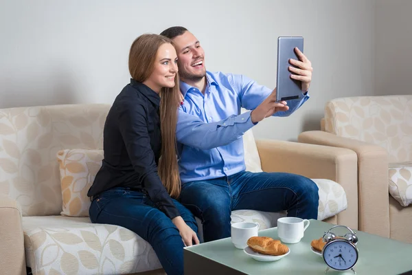 Joven hombre y mujer en el sofá con tableta electrónica — Foto de Stock