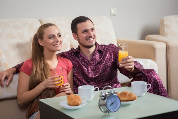 Cute young couple having breakfast, eating croissants, drinking orange juice. — Stok fotoğraf