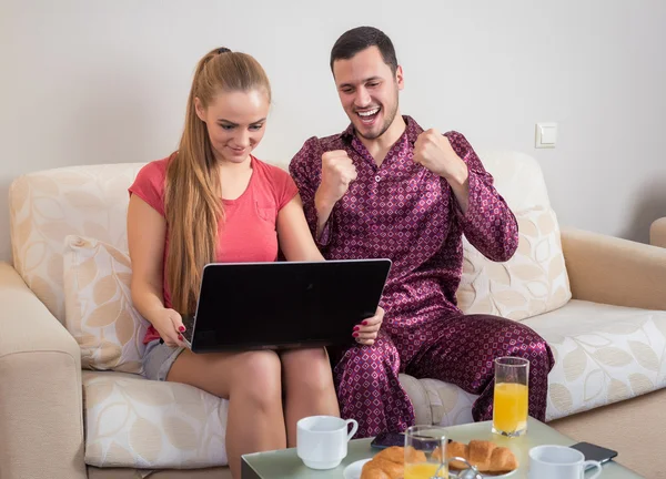 Cute young couple having breakfast, in front of laptop computer — Stock Fotó