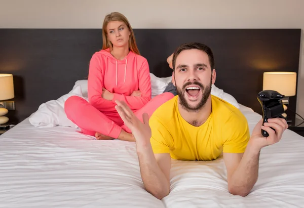 Молодая пара, играющая в видеоигры в постели — стоковое фото