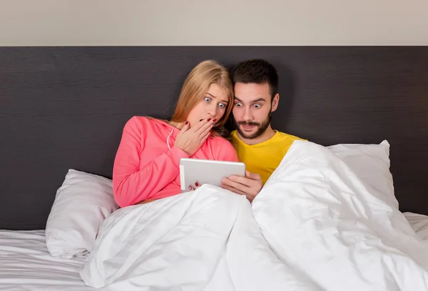 Joven dulce pareja en la cama viendo algo en la tableta Gadget — Foto de Stock