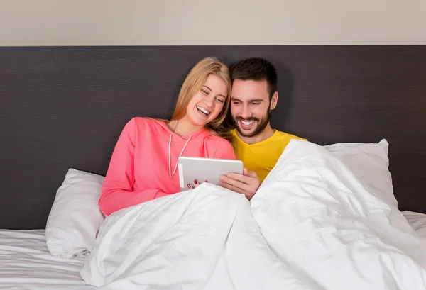 Joven dulce pareja en la cama viendo algo en la tableta Gadget — Foto de Stock