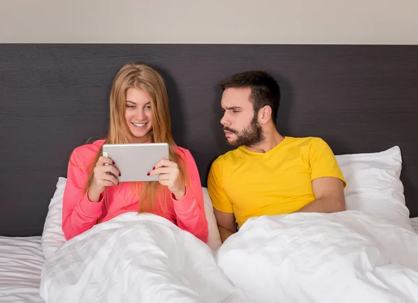 Joven dulce pareja en la cama viendo algo en la tableta Gadget — Foto de Stock