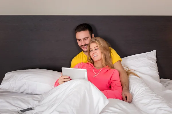 Joven dulce pareja en la cama viendo algo en la tableta Gadget — Foto de Stock