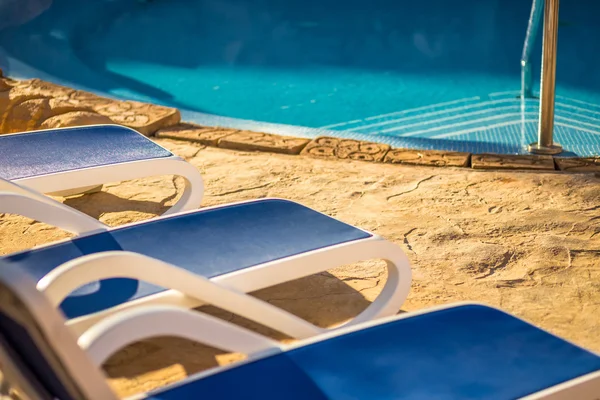 Close up several of sun loungers by a beautiful swimming pool . — стоковое фото