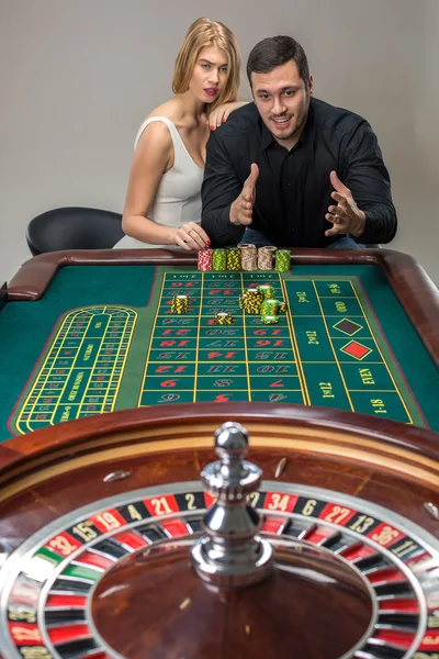 Hombre y mujer animando en la mesa de ruleta en el casino — Foto de Stock