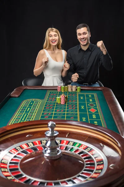 Hombre y mujer animando en la mesa de ruleta en el casino — Foto de Stock