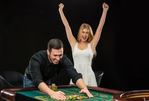 Pareja joven celebrando victoria en la mesa de ruleta en el casino . — Foto de Stock