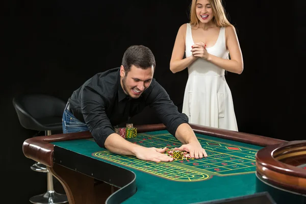 Pareja joven celebrando victoria en la mesa de ruleta en el casino . — Foto de Stock