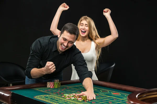 Pareja joven celebrando victoria en la mesa de ruleta en el casino . — Foto de Stock