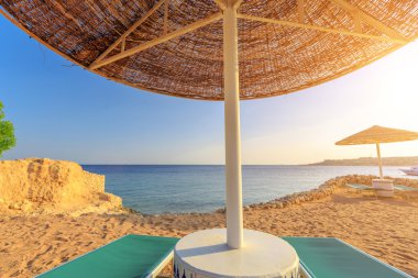 Umbrella and two empty deckchairs on the shore sand beach