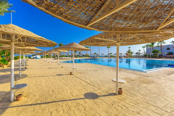 Pohled na krásný bazén, palmy, slunečníky — Stock fotografie