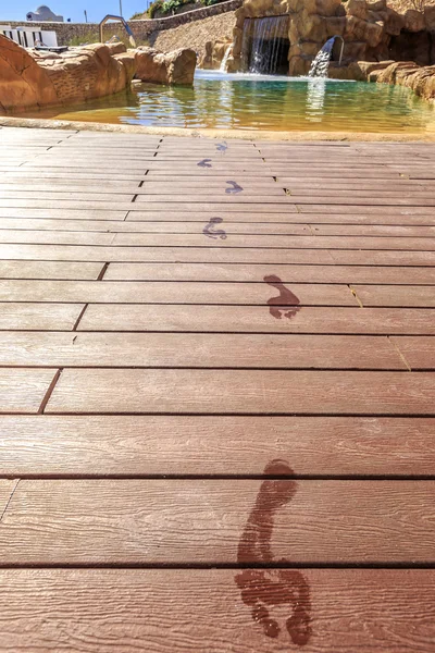 Closeup stopy na dřevěné podlaze za bazén — Stock fotografie